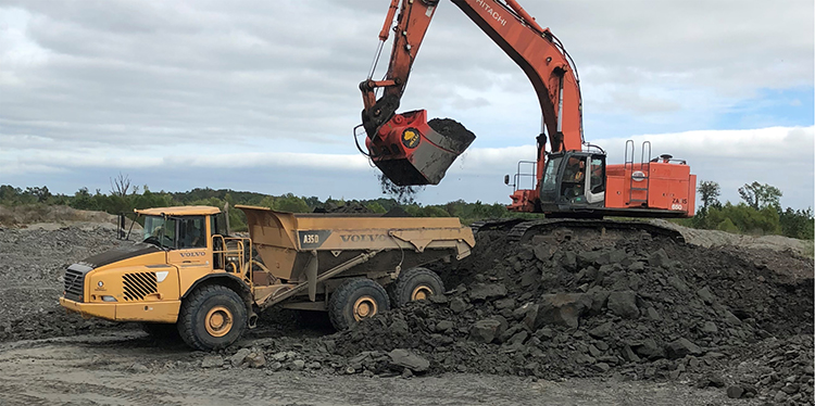 The excavator attachment crushes mined clay down to 4-in. minus while simultaneously loading haul trucks. Photo courtesy of Allu