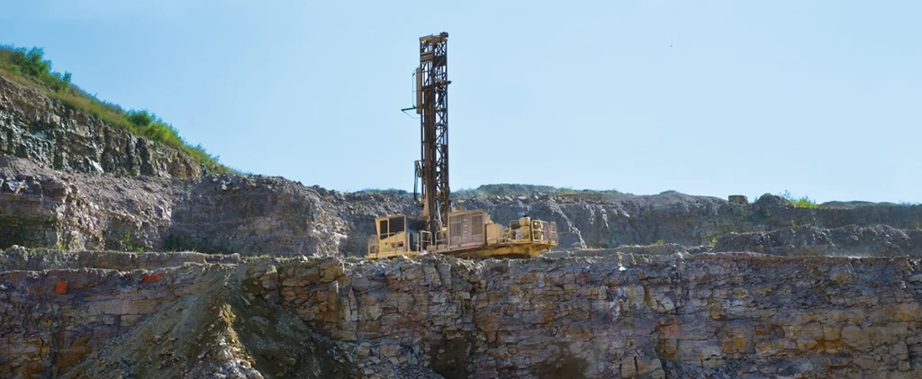 Photo of a drill rig positioned at the bench, preparing blastholes for the next blast.