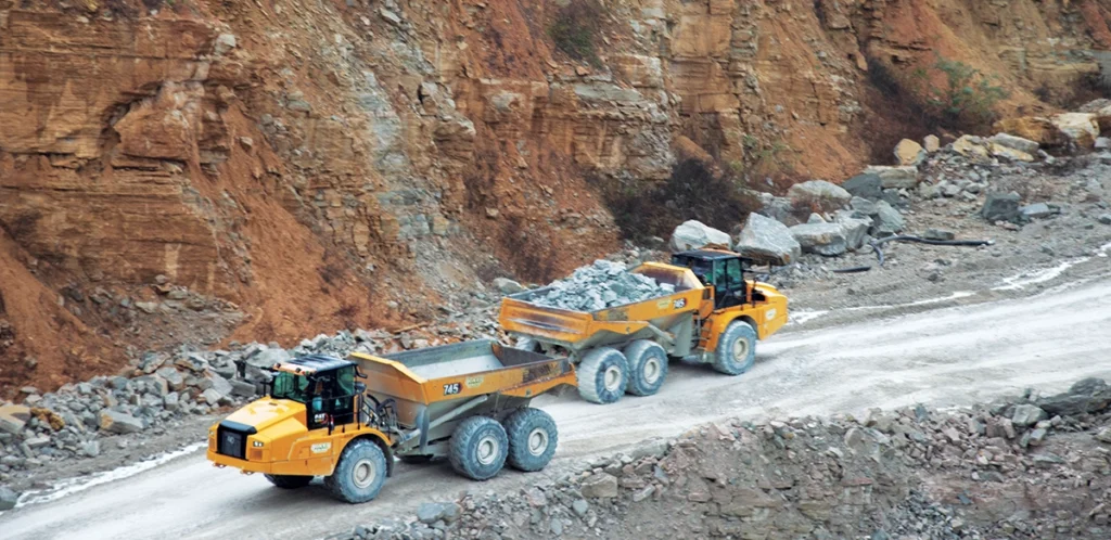 Photo of two haul trucks driving along a haul road